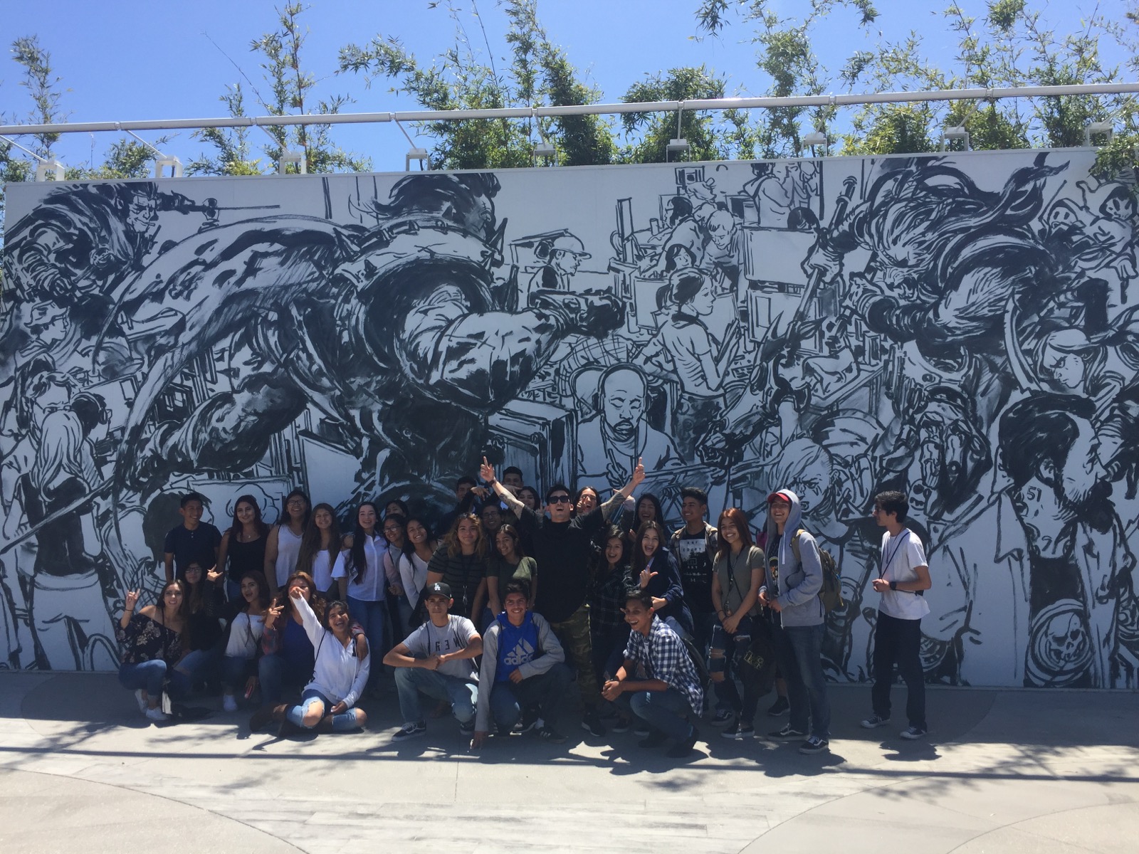 Tim Hirata with a large group of students in front of a black and white mural